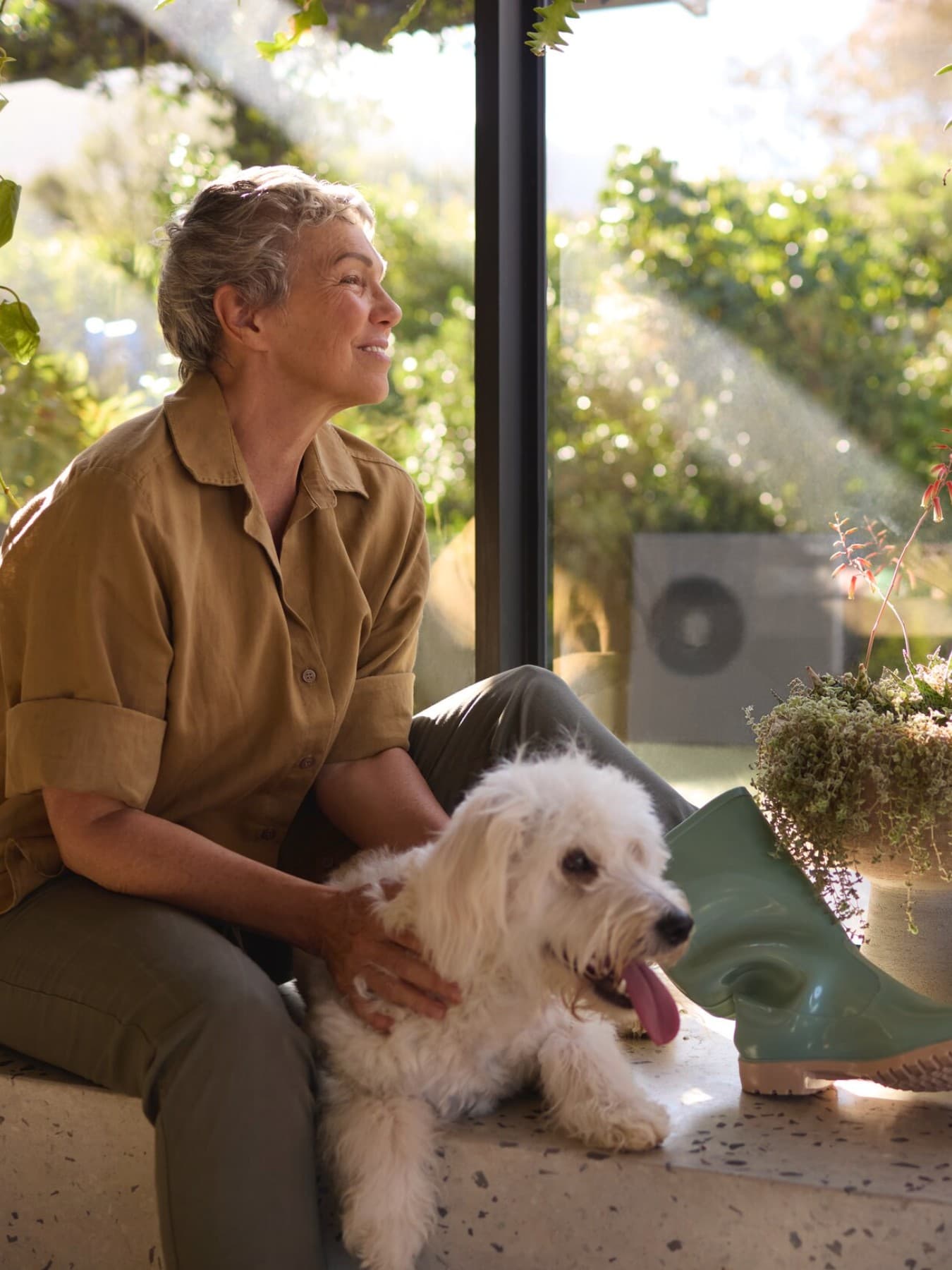 Pompe à chaleur Vaillant aroTHERM plus dans le jardin et femme assise par terre | Vaillant
