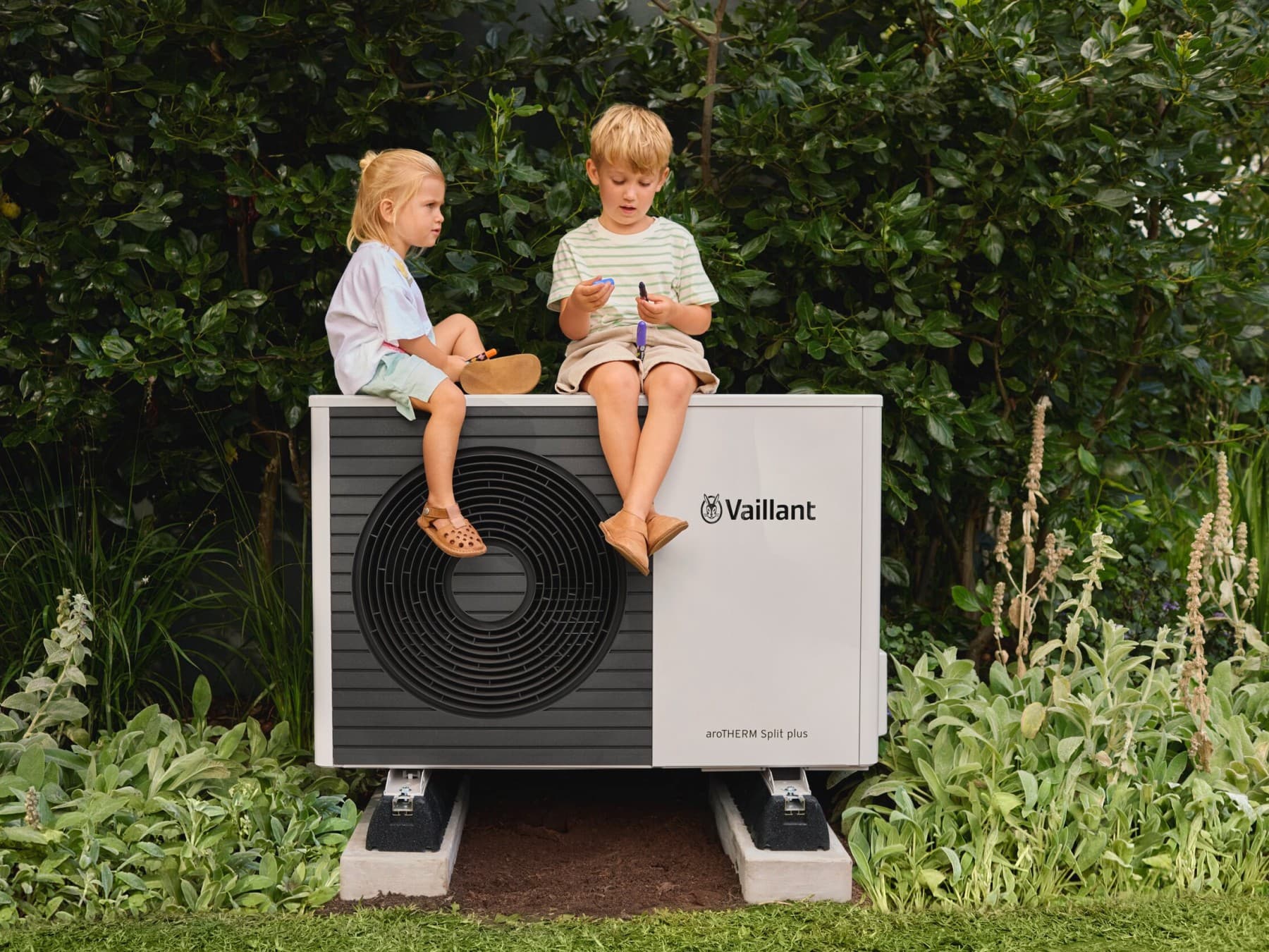 Enfants assis sur une pompe à chaleur | Vaillant