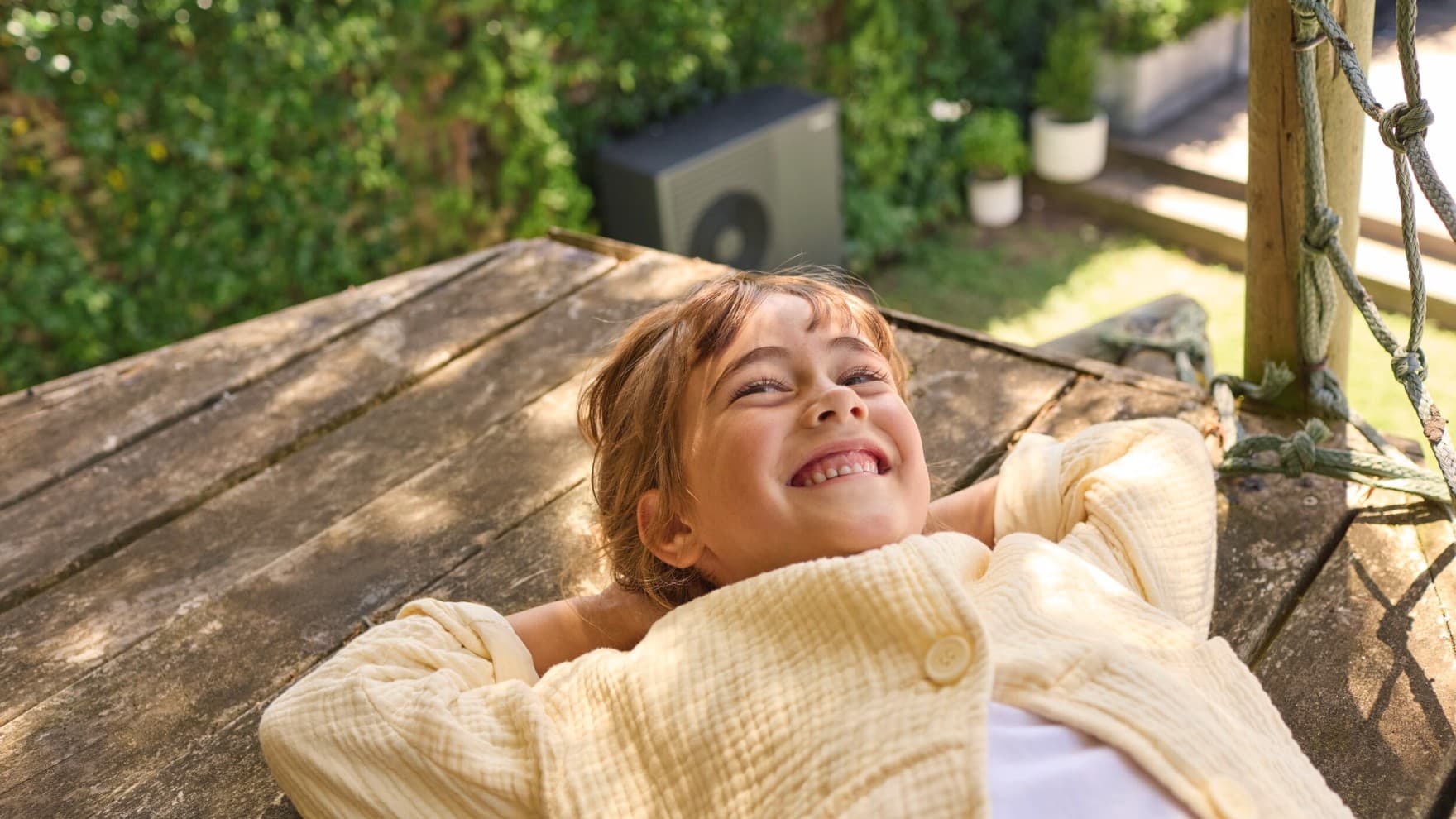 Fille souriante. pompe à chaleur en arrière-plan | Vaillant