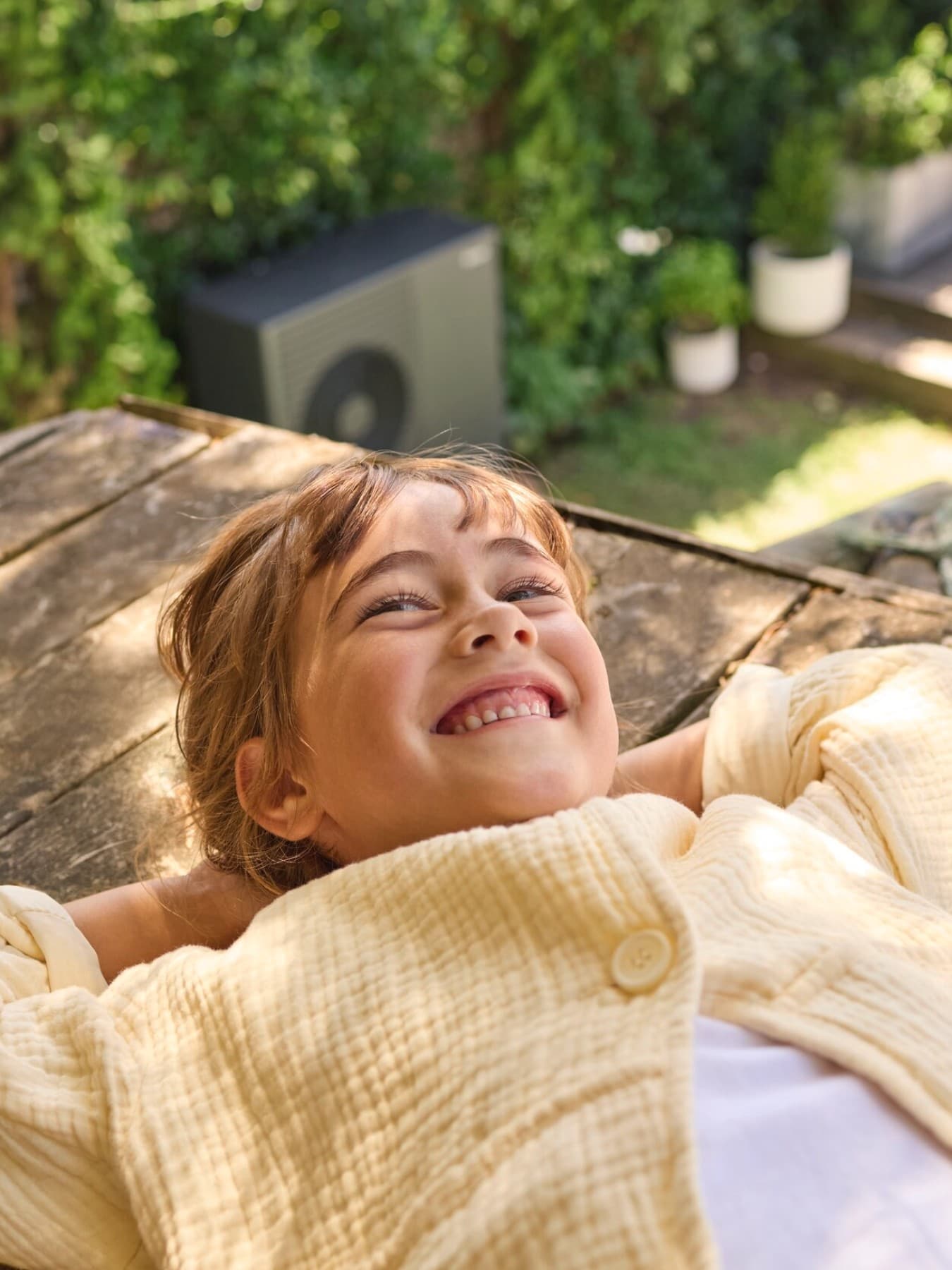 Fille souriante. pompe à chaleur en arrière-plan | Vaillant