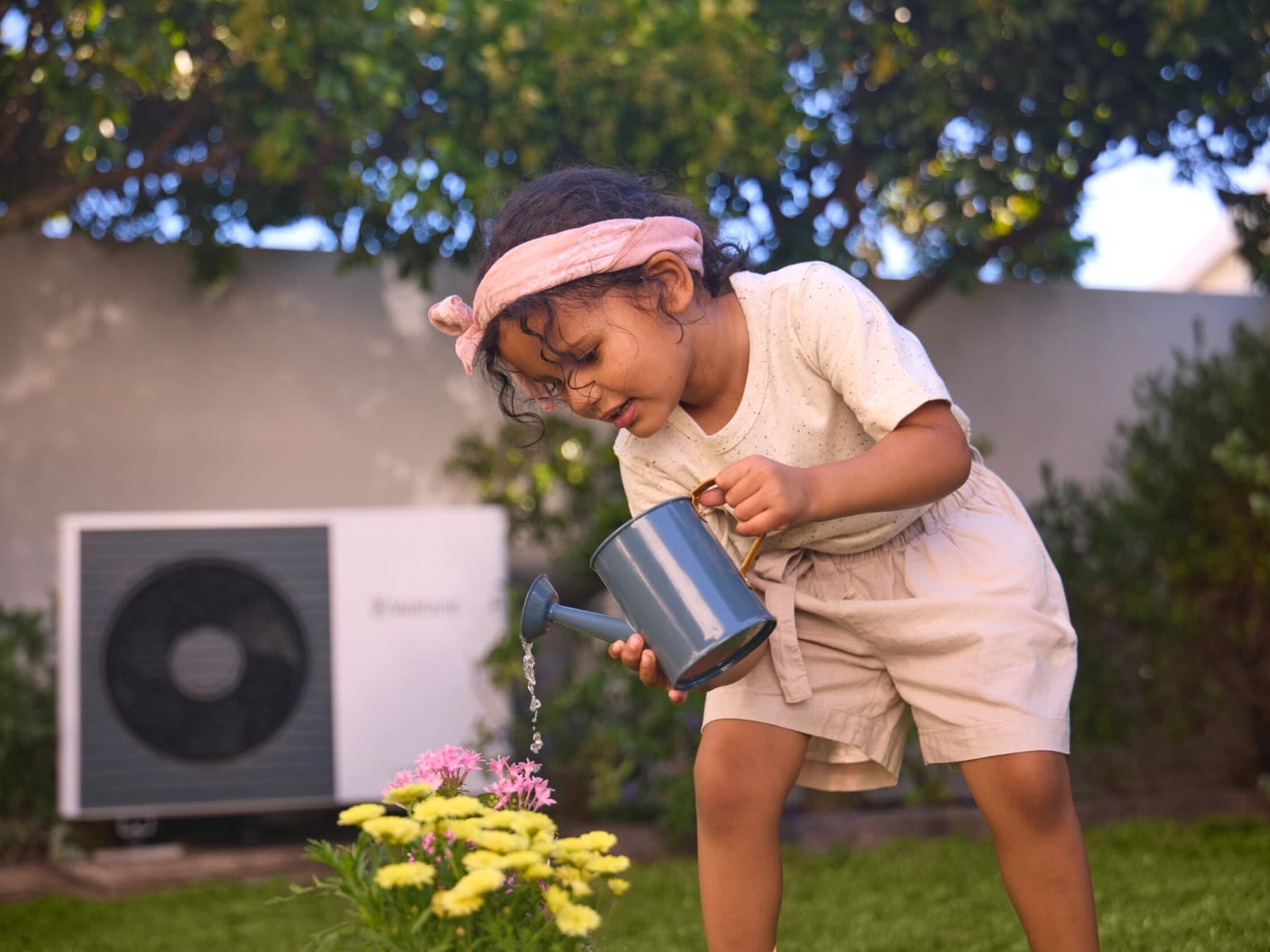 Fille arrosant les fleurs dans le jardin | Vaillant