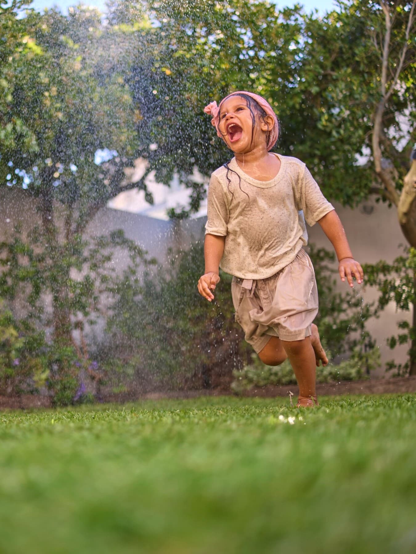 Une petite fille jouant dans son jardin avec une pompe à chaleur en fond | Vaillant