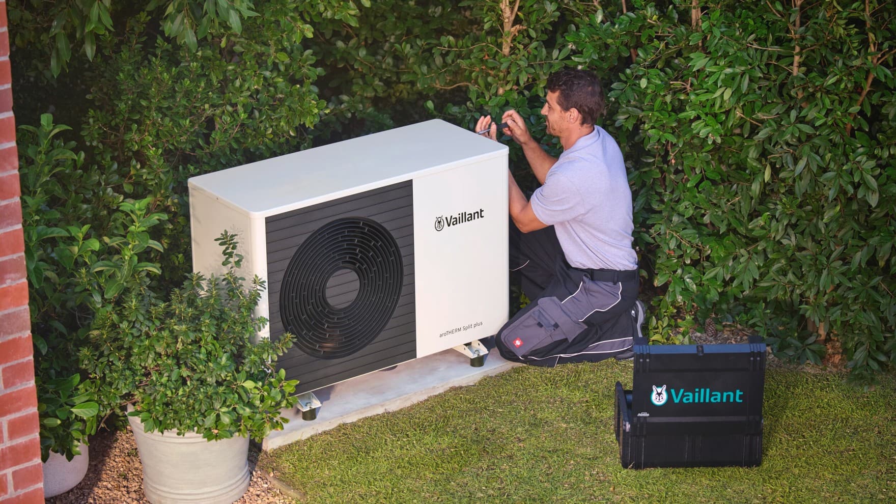 Un installateur vérifiant une pompe à chaleur à l'aide d'un outil | Vaillant