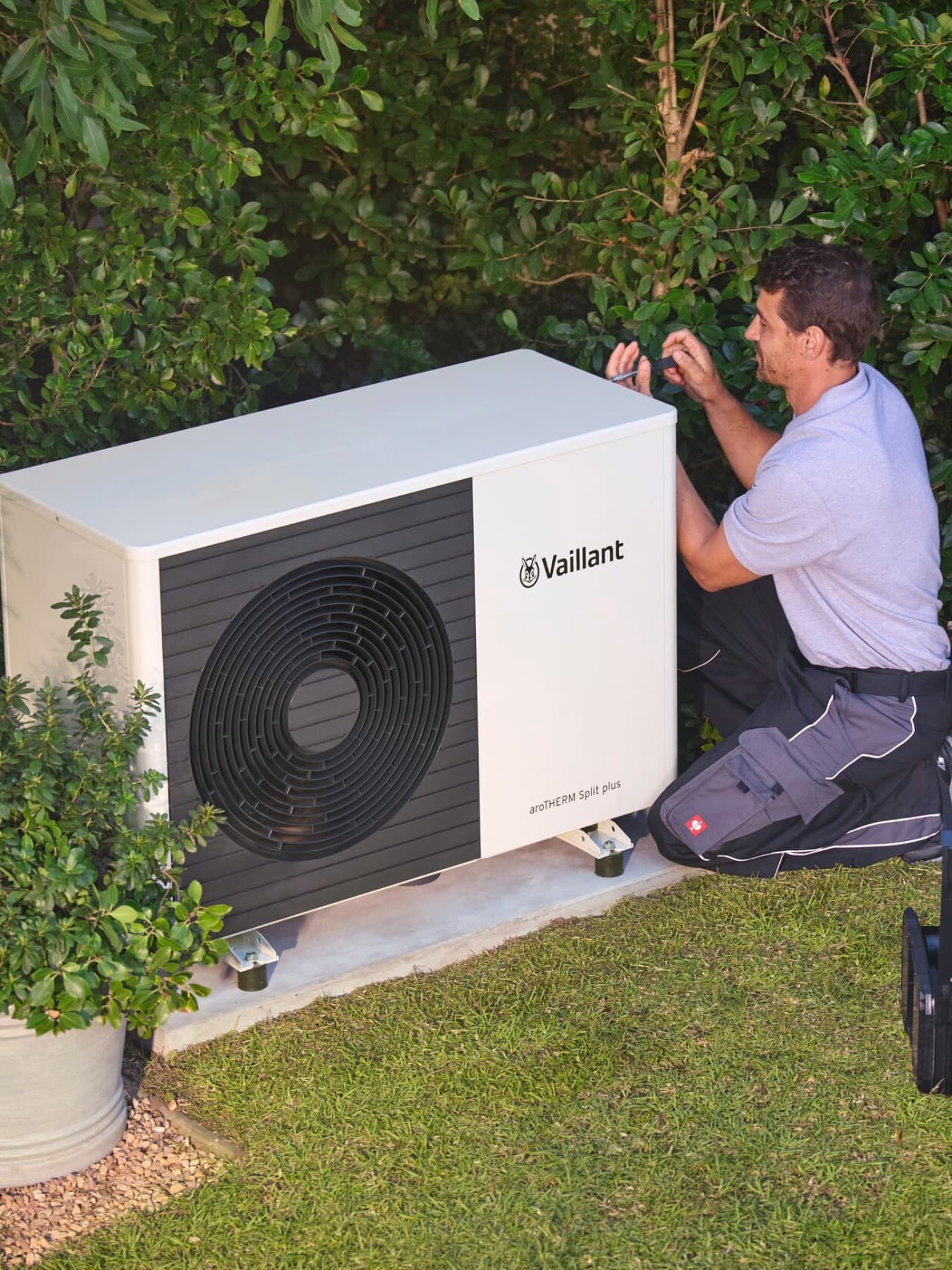 Un installateur vérifiant une pompe à chaleur à l'aide d'un outil | Vaillant