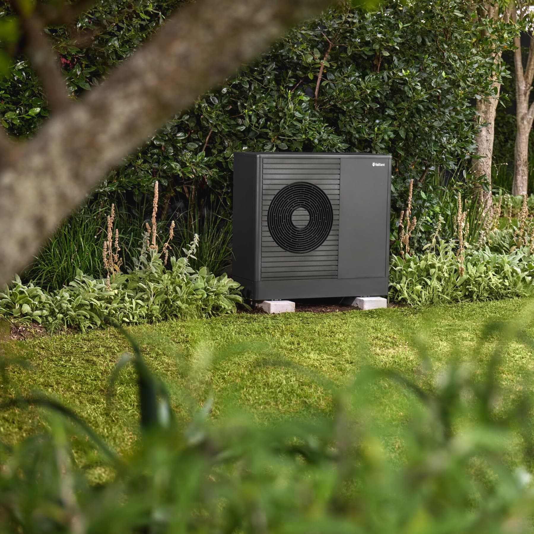 Une pompe à chaleur Vaillant dans le jardin devant une maison | Vaillant
