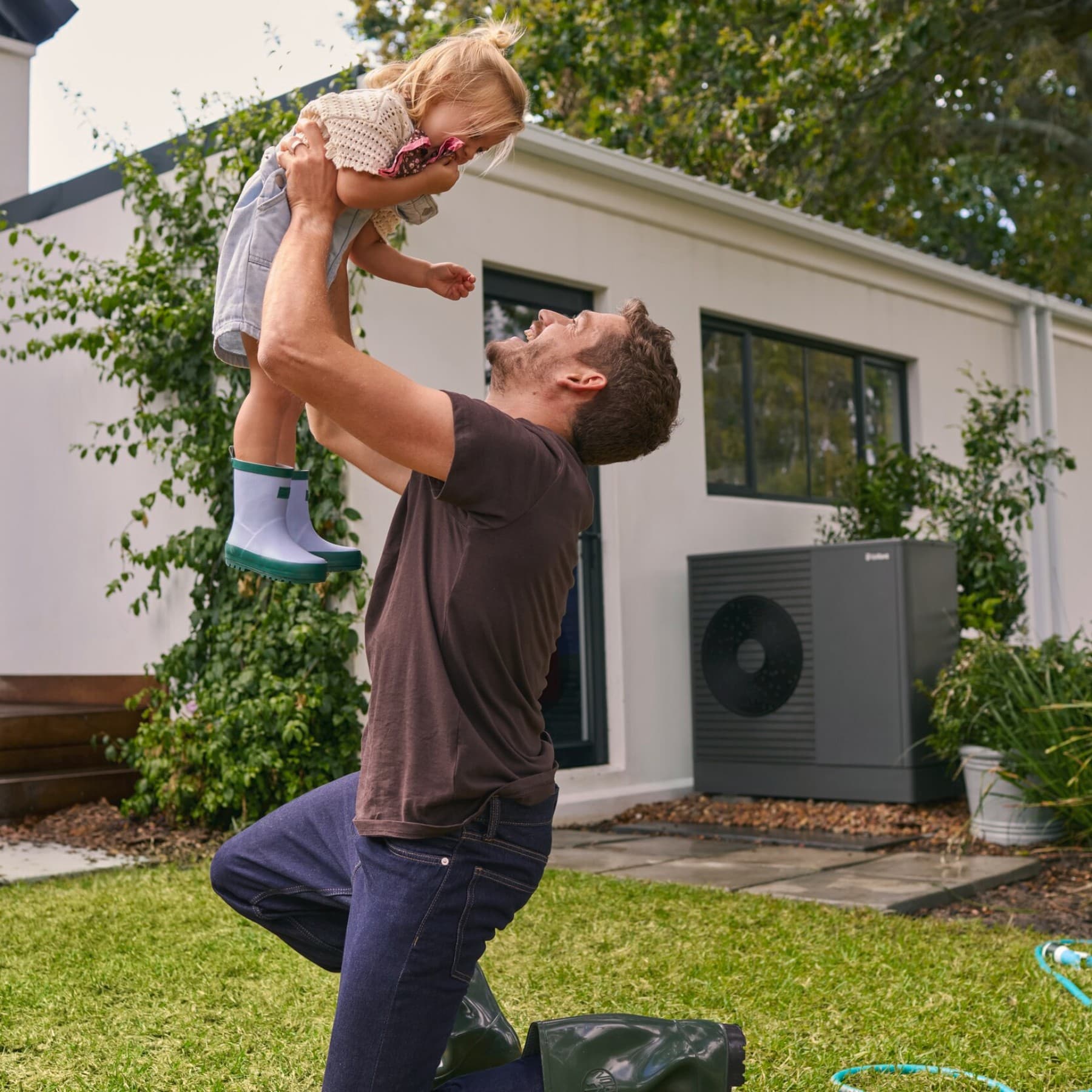 Un homme soulevant un enfant dans un jardin | Vaillant