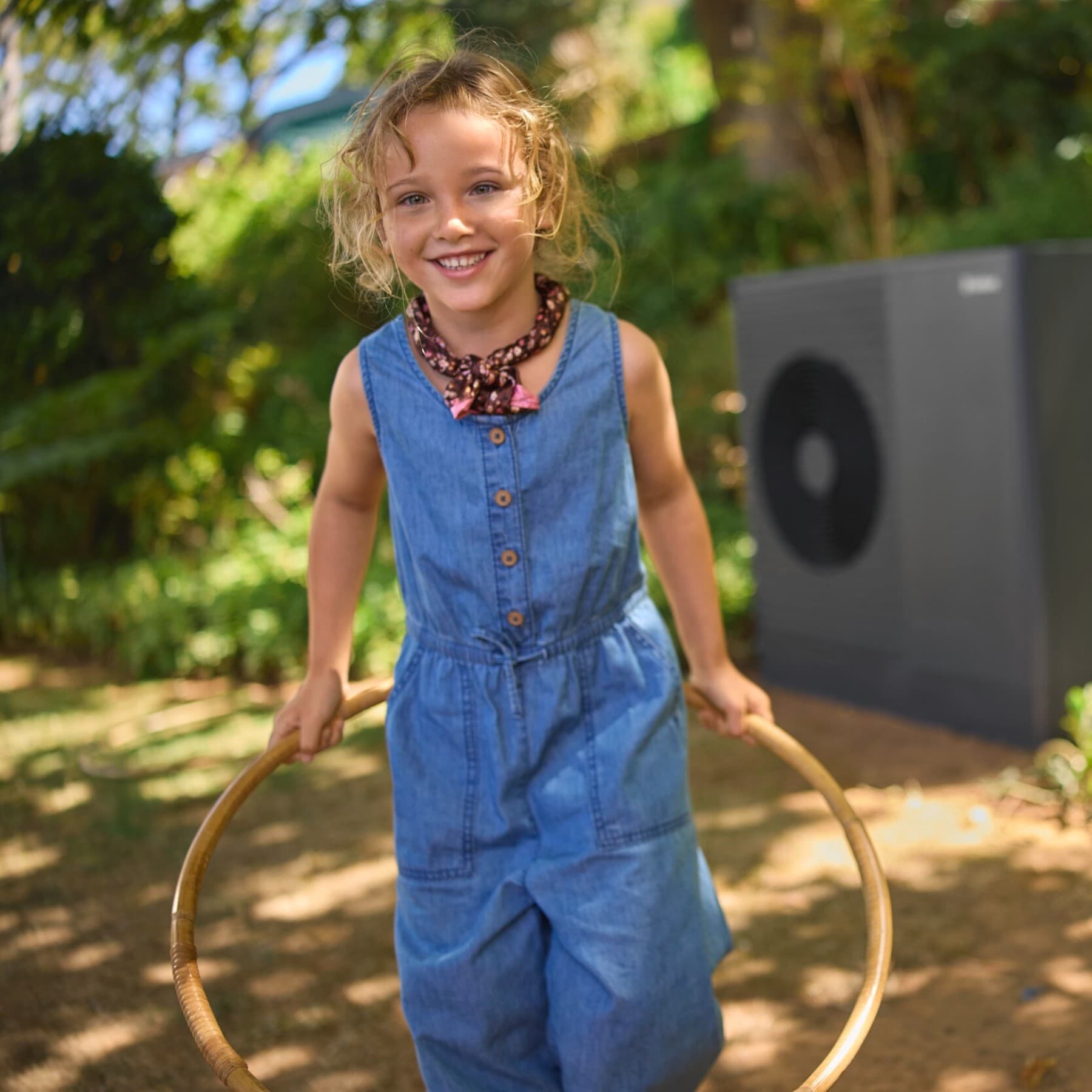 Petite fille jouant dans son jardin avec pompe à chaleur aroTHERM plus en fond | Vaillant