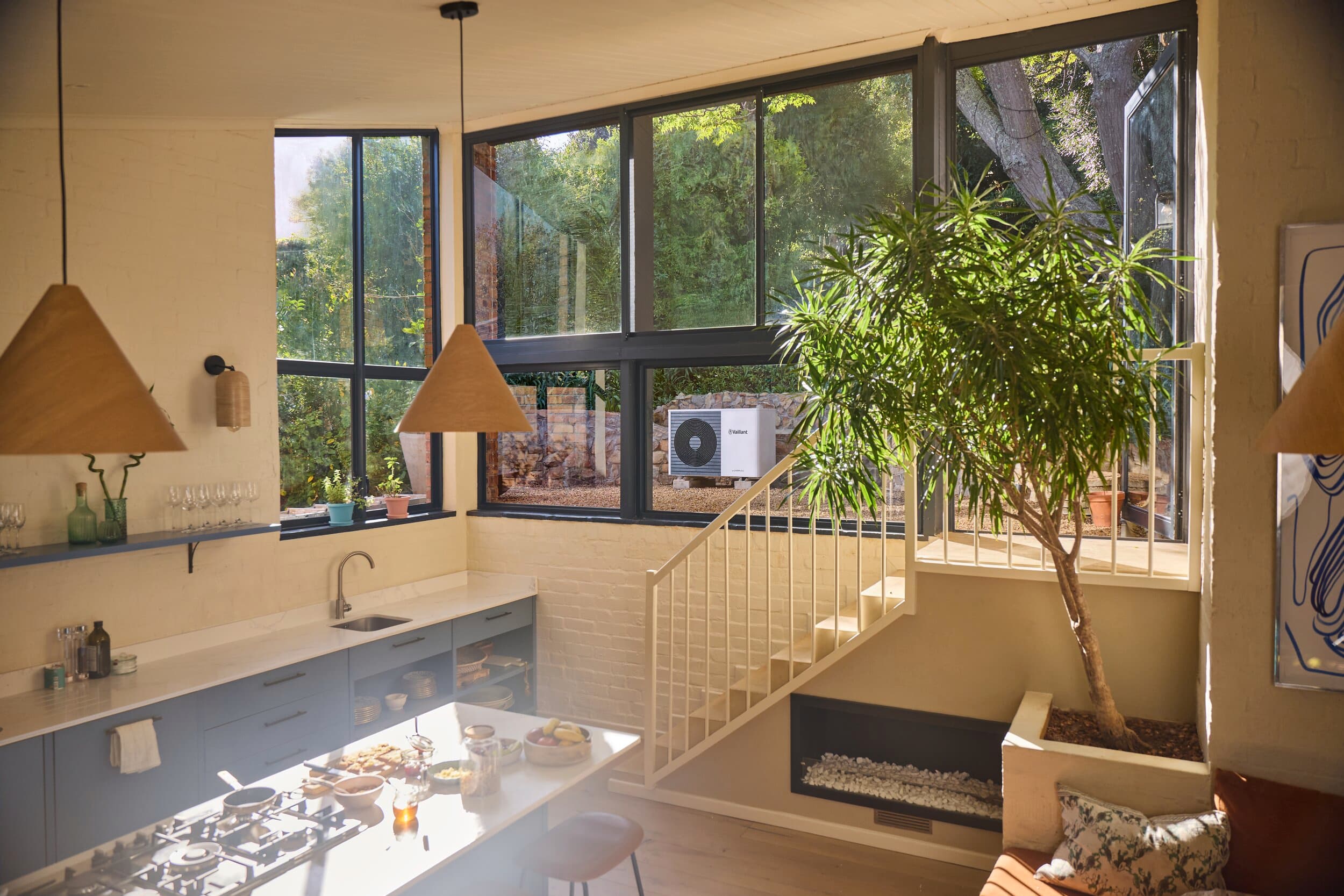 Cuisine dotée d'une grande baie vitrée et offrant une vue sur la pompe à chaleur Vaillant aroTHERM plus | Vaillant