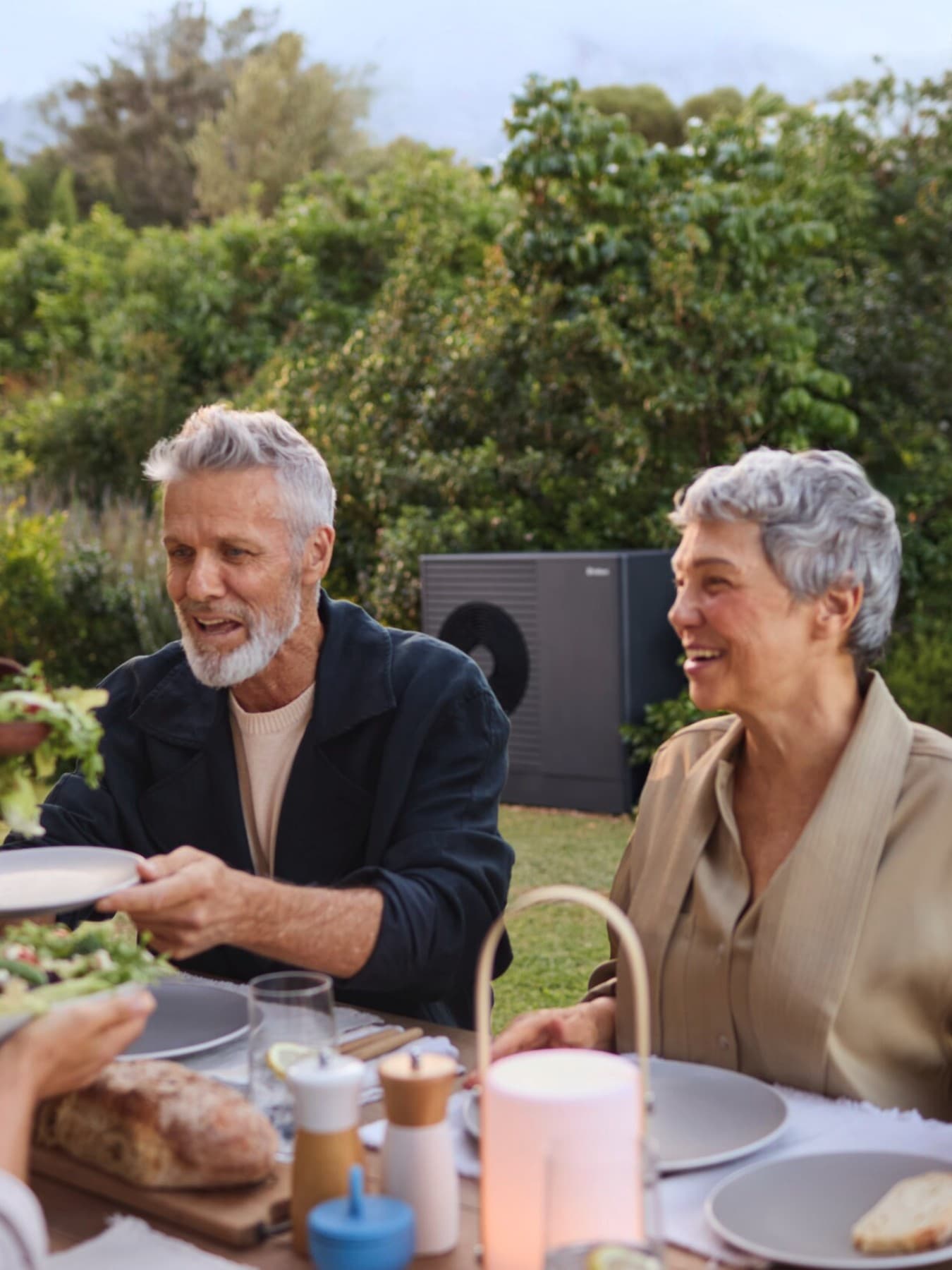 Des gens qui déjeunent dans leur jardin, profitant du silence de leur pompe à chaleur | Vaillant