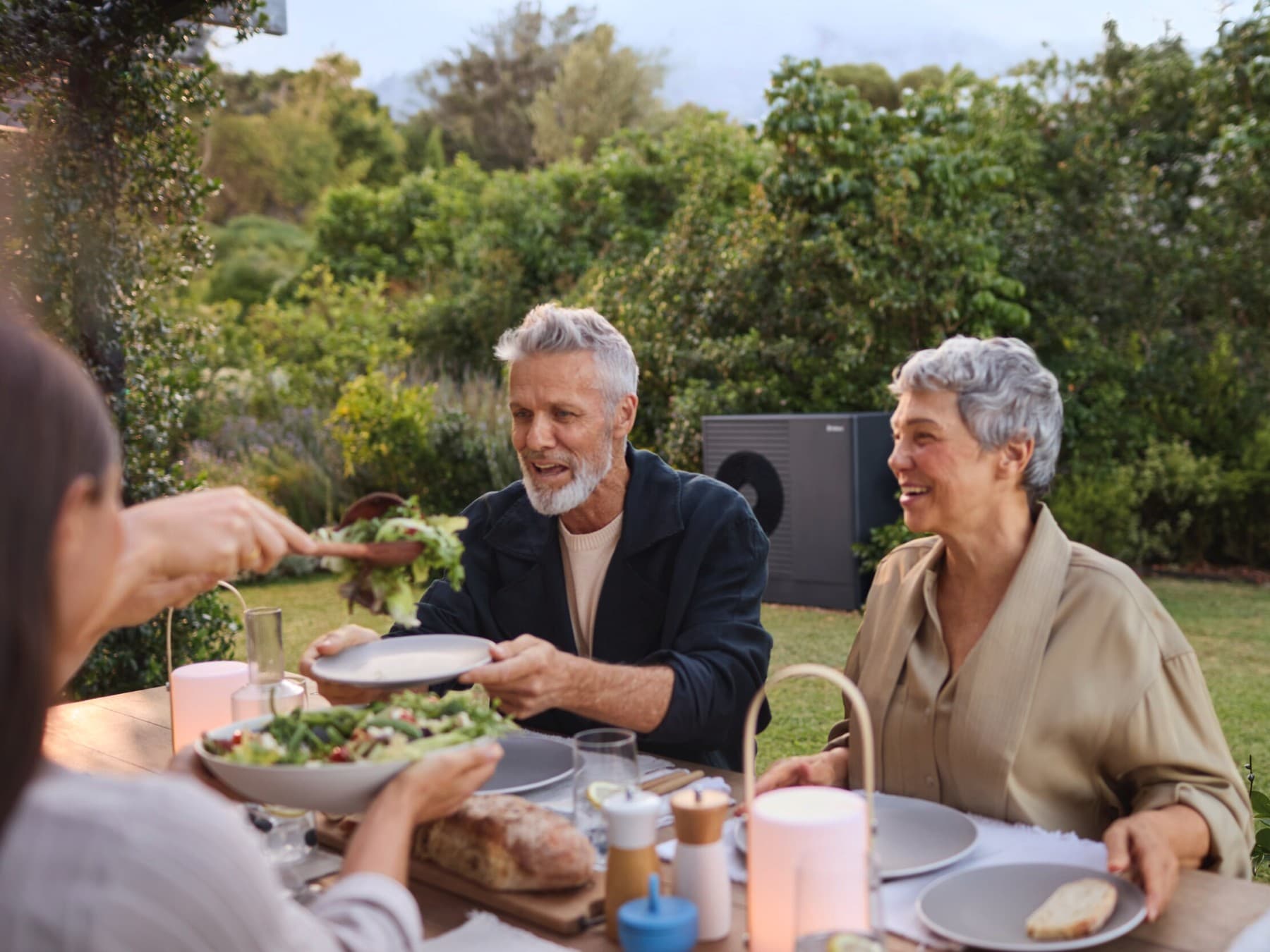 Des gens qui déjeunent dans leur jardin, profitant du silence de leur pompe à chaleur | Vaillant