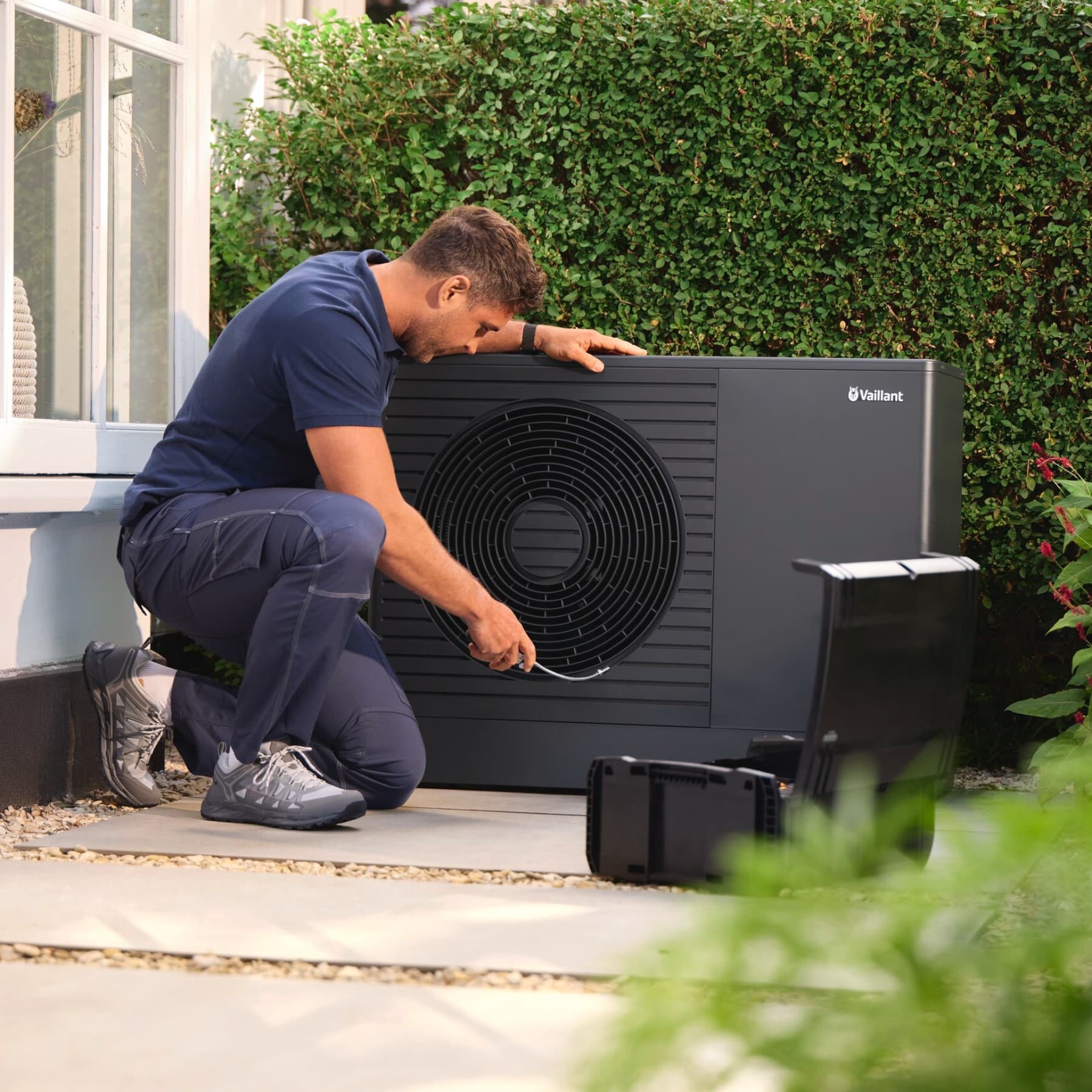 Un installateur en train de vérifier une unité extérieure de pompe à chaleur | Vaillant