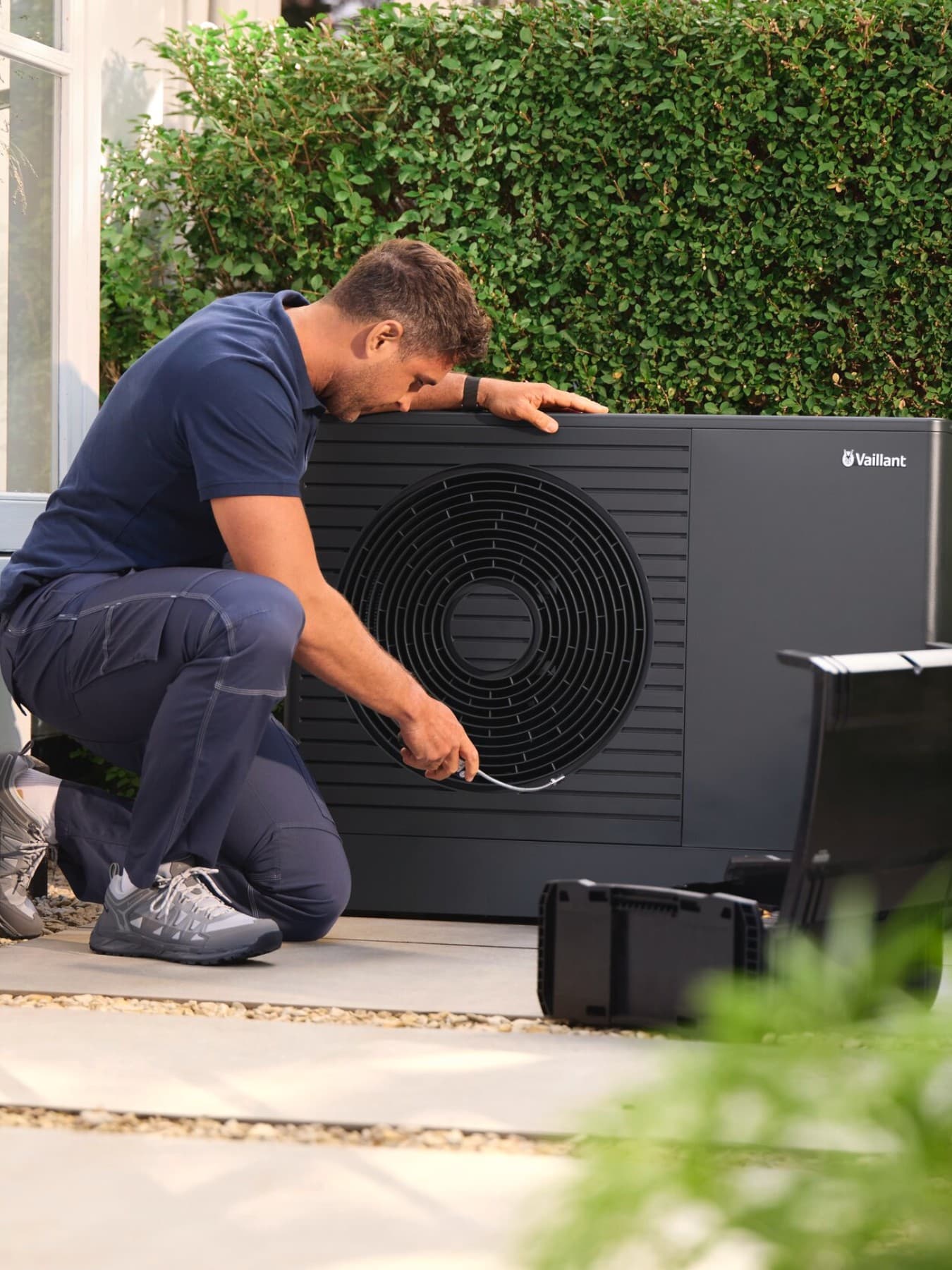 Un installateur en train de vérifier une unité extérieure de pompe à chaleur | Vaillant