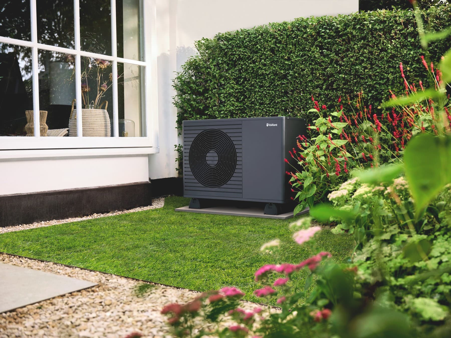 Une unité extérieure de pompe à chaleur dans un jardin | Vaillant