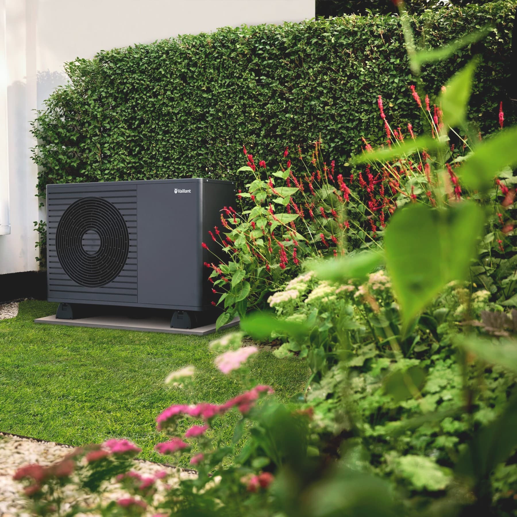 Une unité extérieure de pompe à chaleur dans un jardin | Vaillant