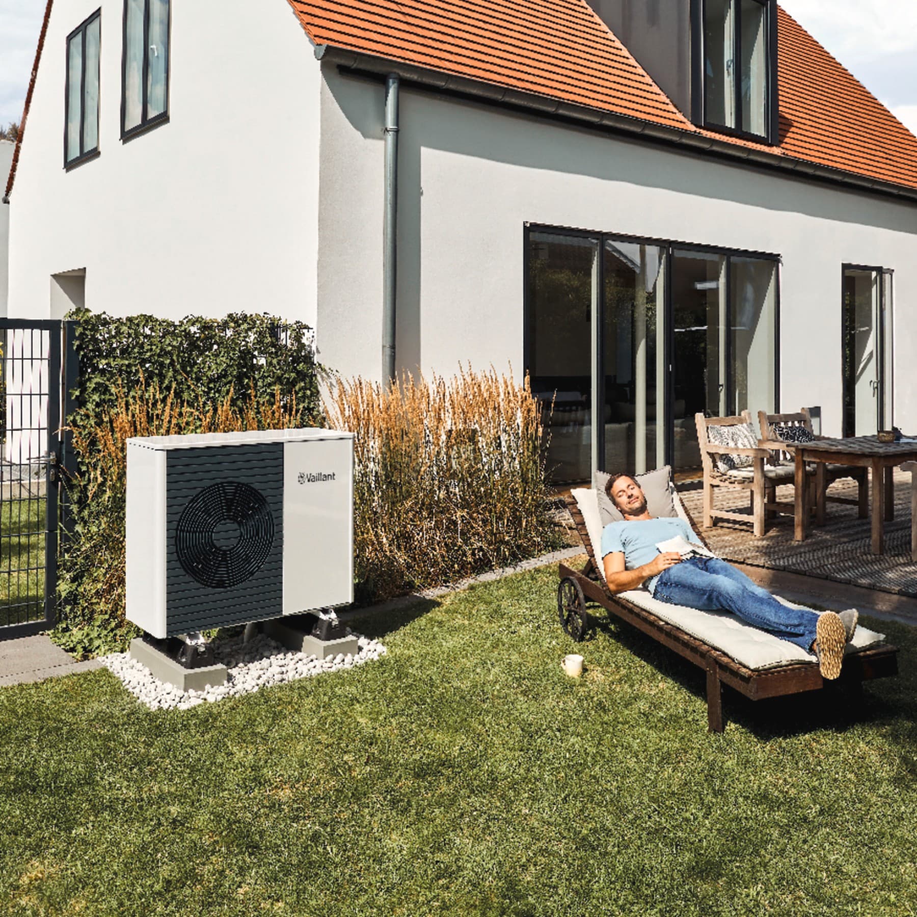 Un homme se repose dans son jardin à côté d'une pompe à chaleur | Vaillant
