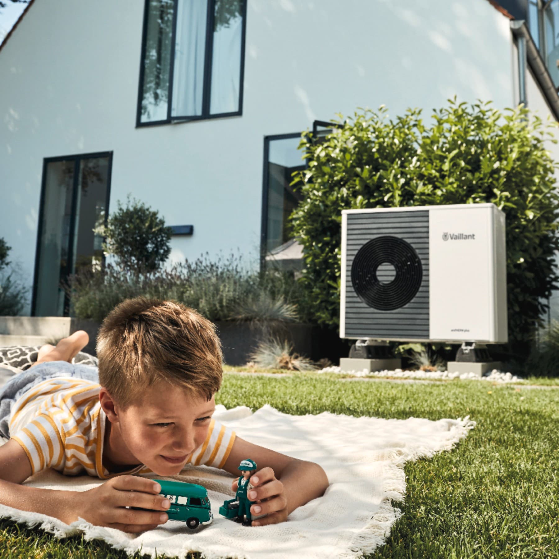 Enfant jouant dans son jardin avec une pompe à chaleur en fond | Vaillant