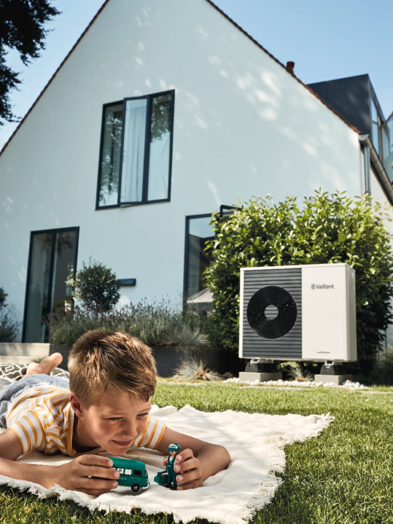 Enfant jouant dans son jardin avec une pompe à chaleur en fond | Vaillant