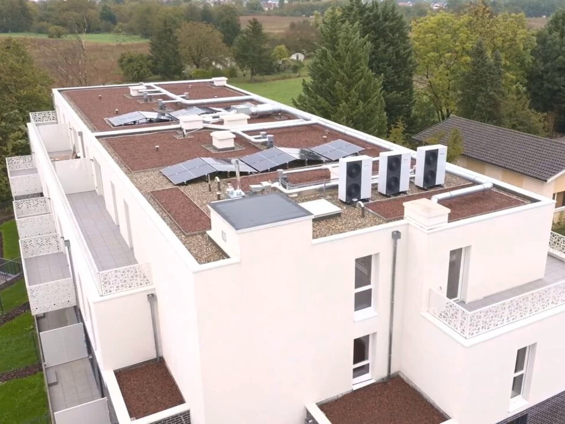 Un bâtiment vu du ciel sur lequel des pompes à chaleur et des panneaux photovoltaïques sont installés sur le toit | Vaillant