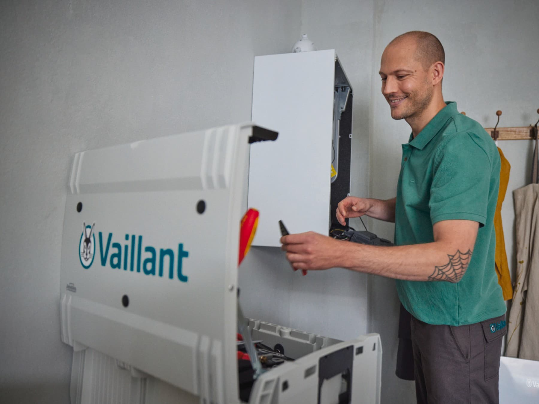 Un SAV est en train de dépanner un chauffe-eau gaz dans une buanderie | Vaillant