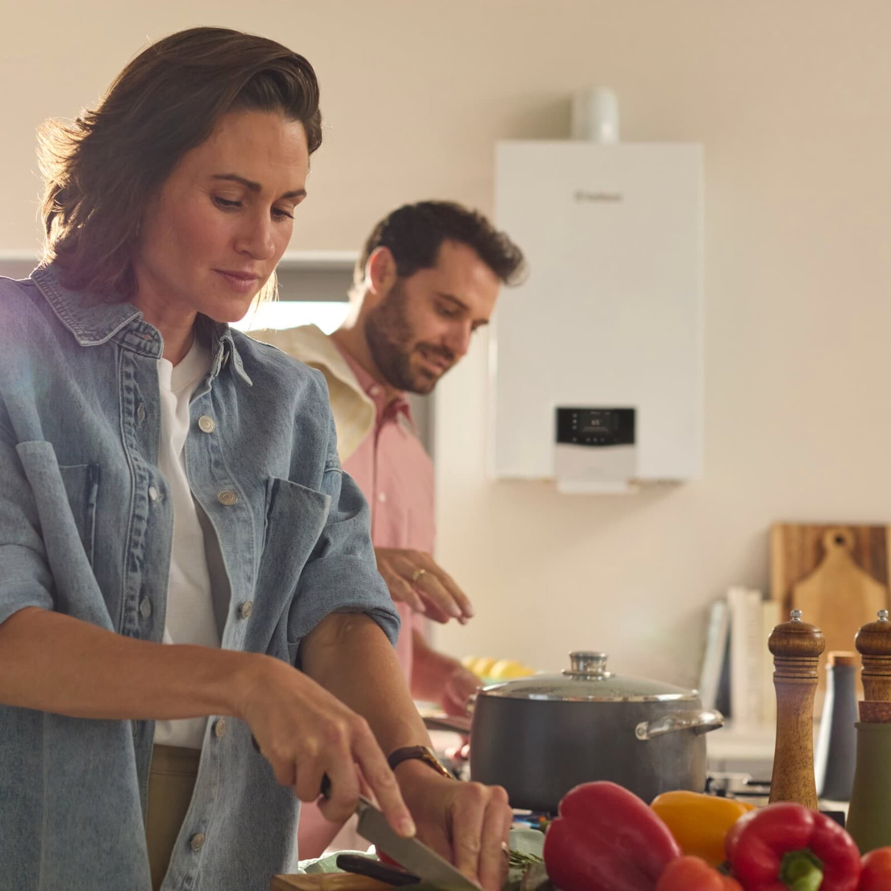 Un homme et une femme cuisinant devant une chaudière | Vaillant