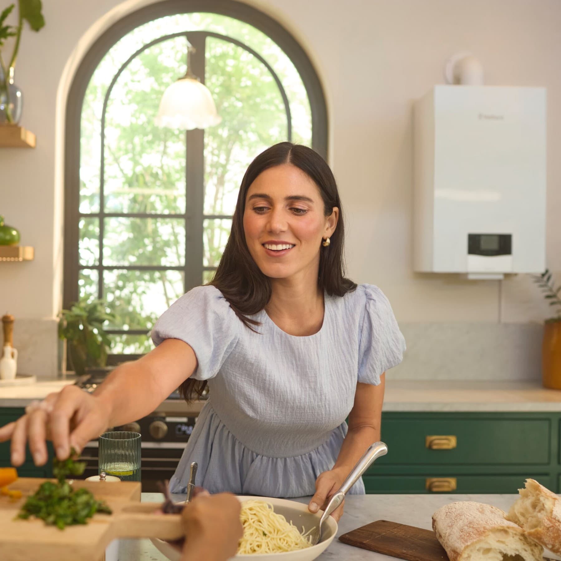 Une femme est dans sa cuisine avec une chaudière gaz au mur | Vaillant