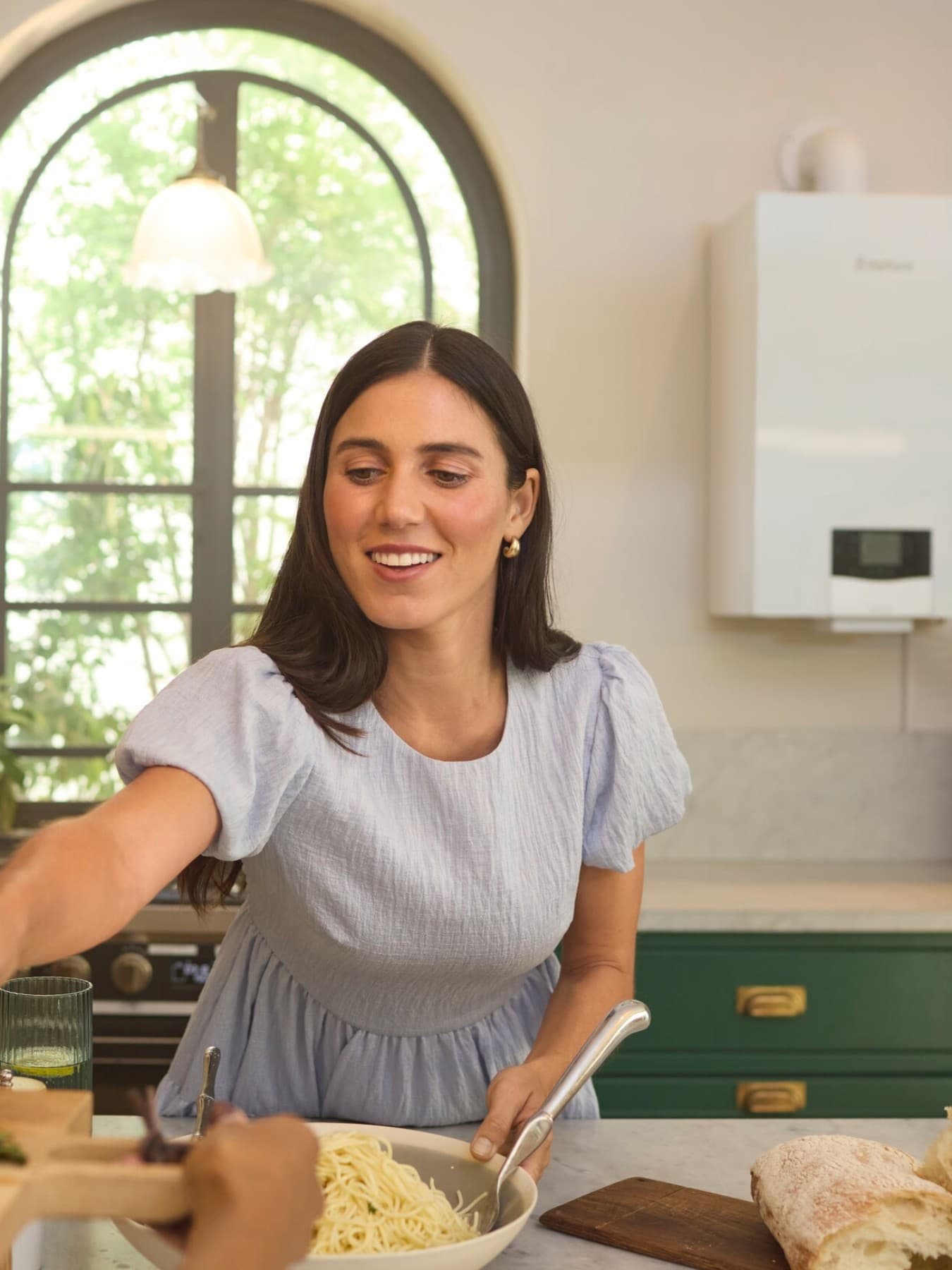 Femme dans une cuisine devant une chaudière | Vaillant