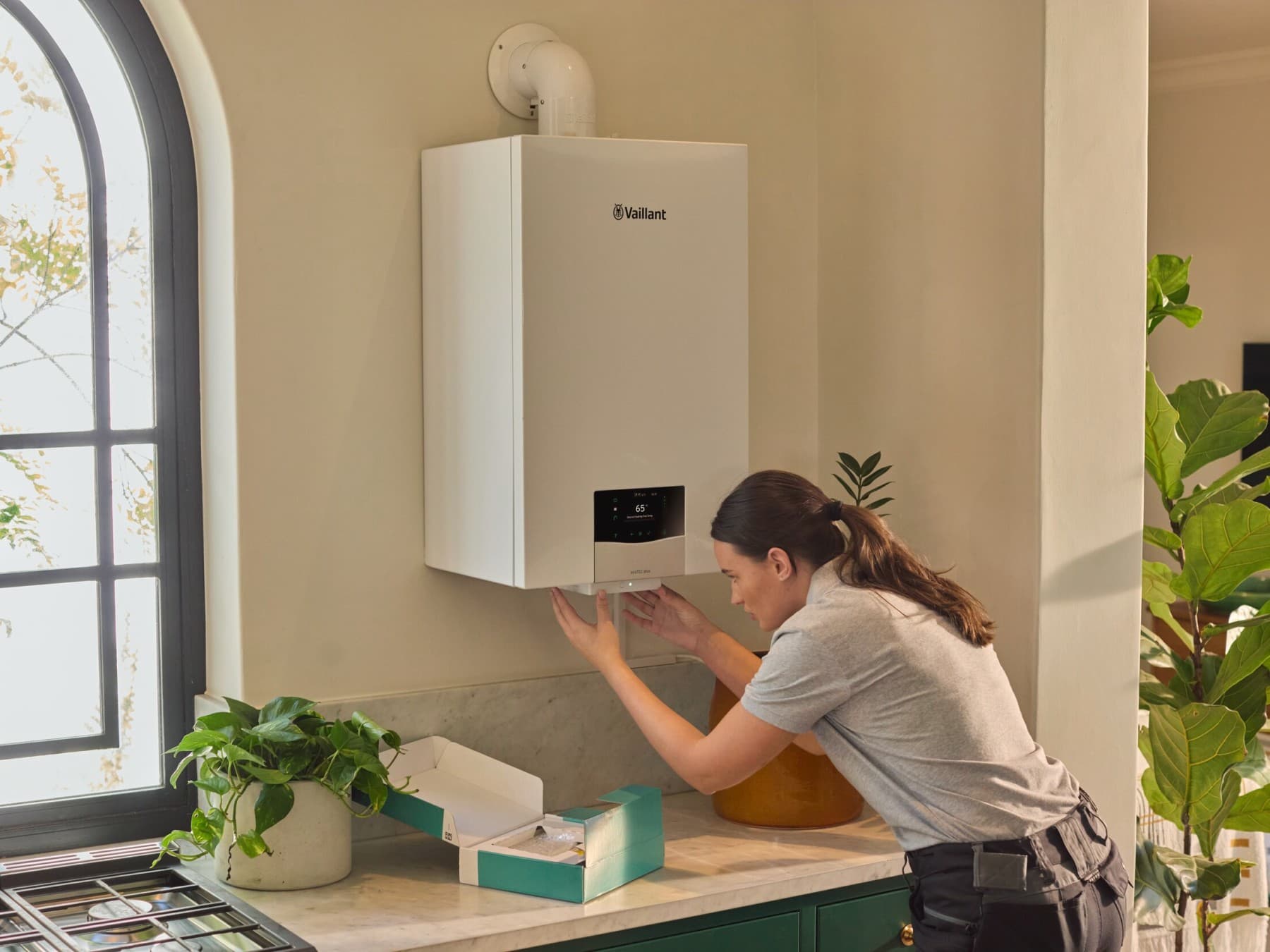 Une réparatrice de chaudière intervient dans une cuisine | Vaillant