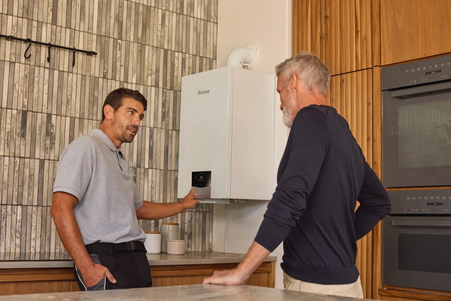 Un installateur expliquant le fonctionnement d'une chaudière à un client | Vaillant