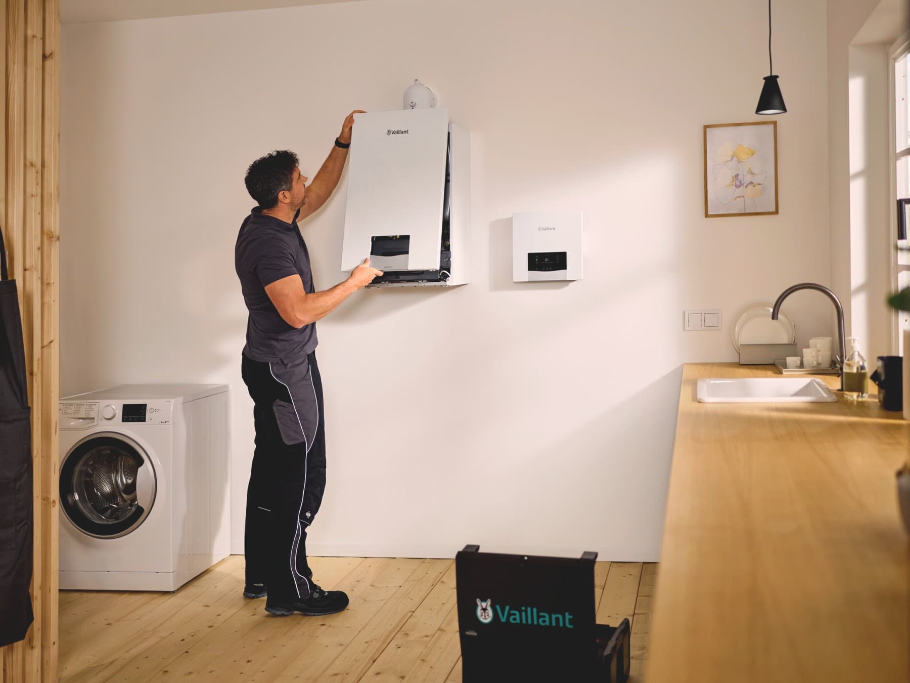 Un chauffagiste entretient une chaudière dans une cuisine | Vaillant