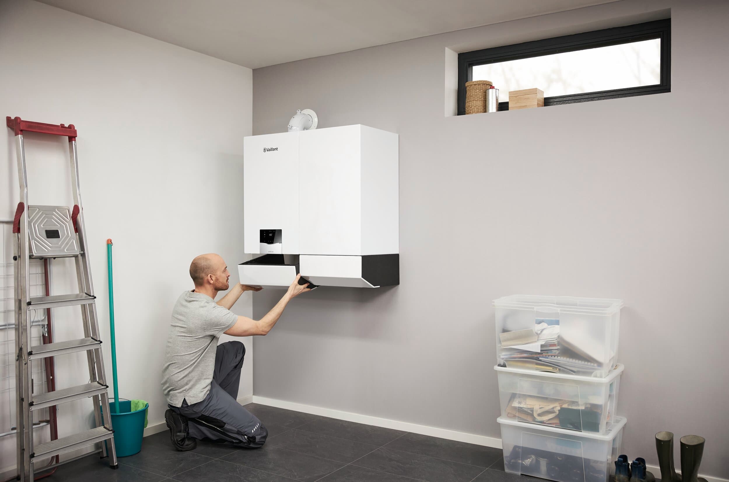 Installateur fixant actoSTOR et ecoTEC plus au mur d'un garage | Vaillant